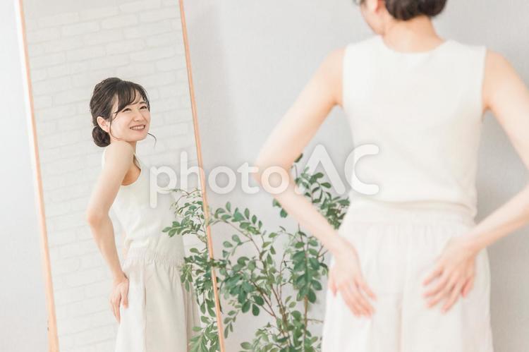 鏡を見てお尻をチェックするアジア人女性 ヒップアップ,お尻,ヒップの写真素材