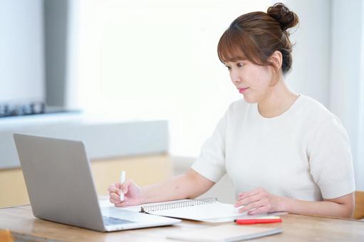 ペンを持ちパソコンを見つめるお団子ヘアの女性 女性,ノートパソコン,見るの写真素材
