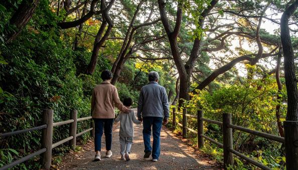 なごやかな雰囲気で森林を歩く家族の後ろ姿の写真