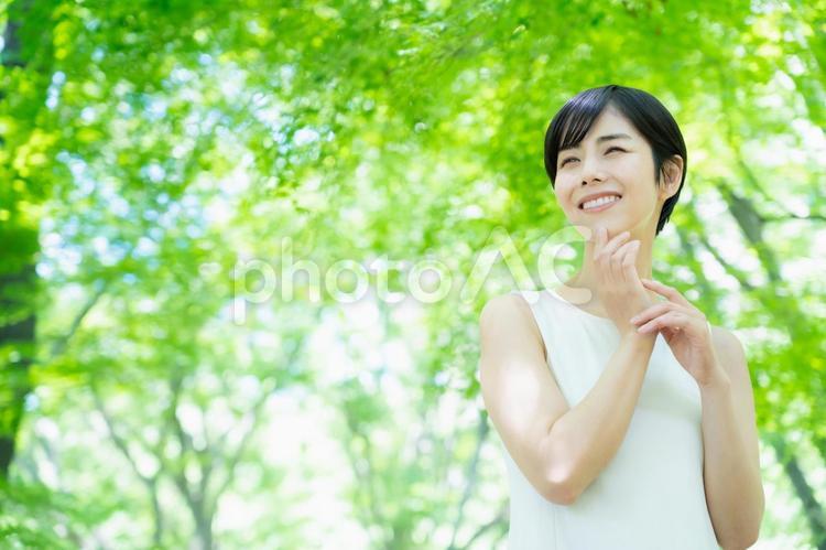 緑の中でスキンケアをする若い女性 ビューティー,女性,スキンケアの写真素材