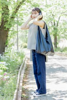 新緑の中ヘッドフォンで音楽を聴く若い女性 新緑の中ヘッドフォンで音楽を聴く若い女性 女性,外出,ヘッドフォンの写真素材