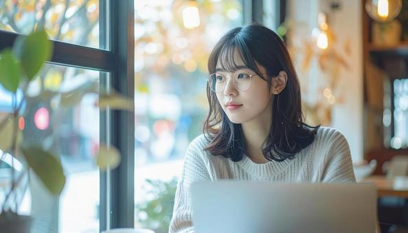 カフェでノートパソコンを使う日本人女性 カフェでノートパソコンを使う日本人女性の写真