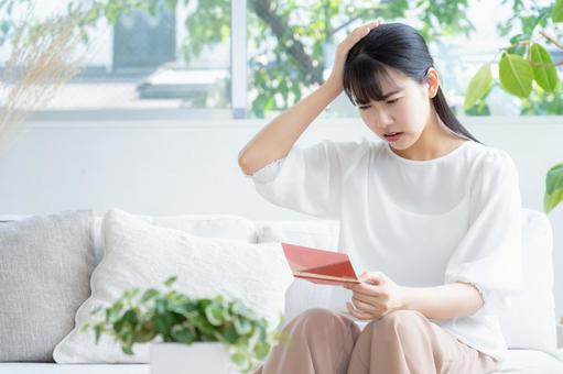 リビングで貯金通帳を見る若い女性 リビングで貯金通帳を見る若い女性 女性,リビング,ライフスタイルの写真素材
