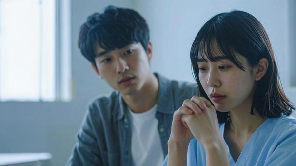 落ち込む彼女と、なぐさめる彼氏の写真