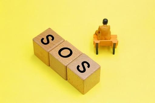 SOSと書かれたブロックと落ち込む人 SOSと書かれたブロックと落ち込む人の写真