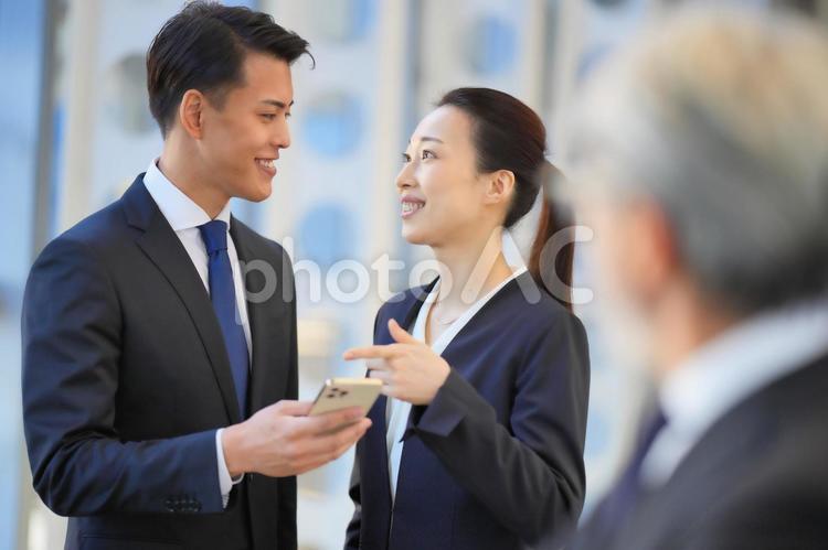 スマートフォンを見ながら話すビジネスマン ビジネスマン,ビジネスウーマン,男女の写真素材