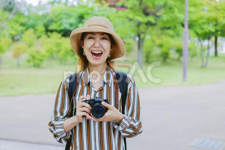 カメラを持って微笑む女性 カメラ,一眼レフ,一眼レフカメラの写真素材