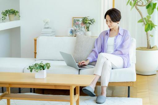 部屋でノートパソコンを使うミドル女性 部屋でノートパソコンを使うミドル女性 女性,笑顔,テーブルの写真素材
