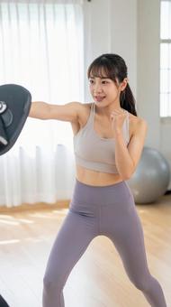 ジムでボクササイズをする若い女性 ジムでボクササイズをする若い女性の写真