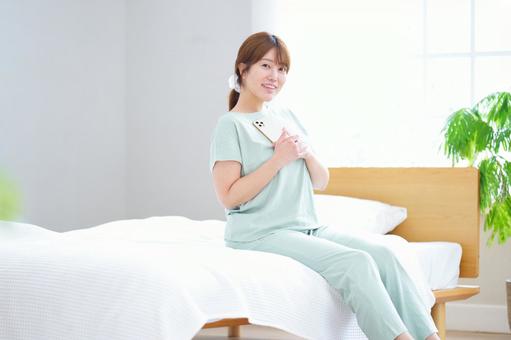 スマホを胸に当て持つ笑顔の女性の写真