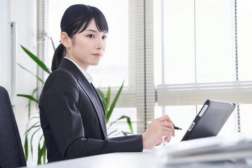 Japanese female business woman who converts paper materials into data using a tablet in the office Japanese female business woman who converts paper materials into data using a tablet in the office