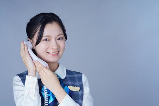 青いリボンの制服の女性が頬に手を添えて笑うの写真