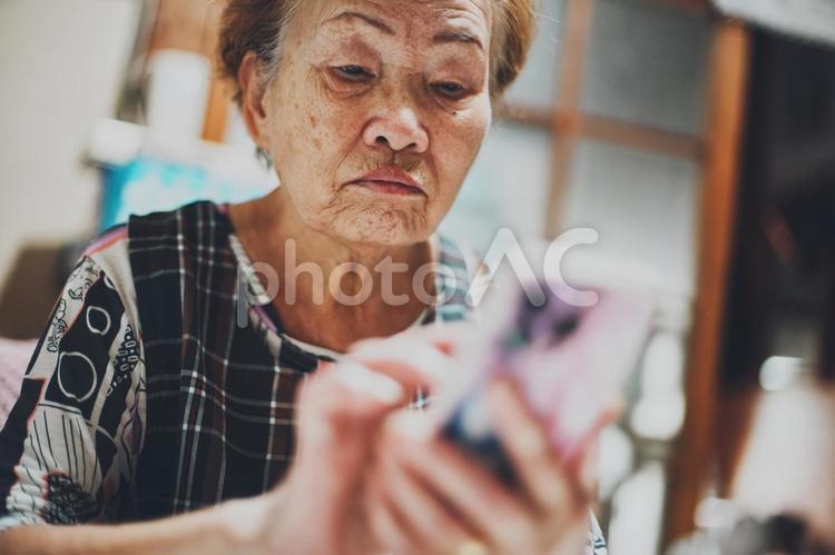 真顔でスマートフォンを見ているシニア女性 スマホ,シニア,高齢者の写真素材