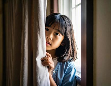 カーテンの陰から顔を出す不安げな少女 カーテンの陰から顔を出す不安げな少女の写真