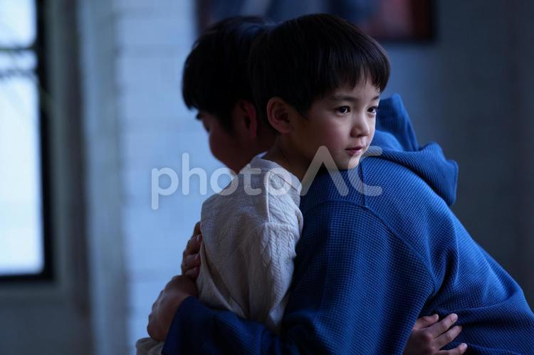 暗いところで抱き合う親子 親子,男の子,小学生の写真素材