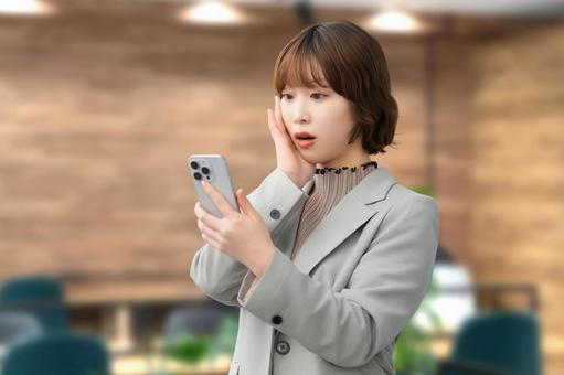 スマホの画面を見て驚くビジネスウーマン 女性,スマホ,スマートフォンの写真素材