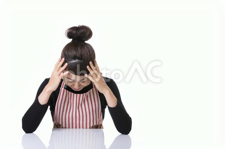 頭を抱えるエプロン姿の女性 女性,人物,考えるの写真素材