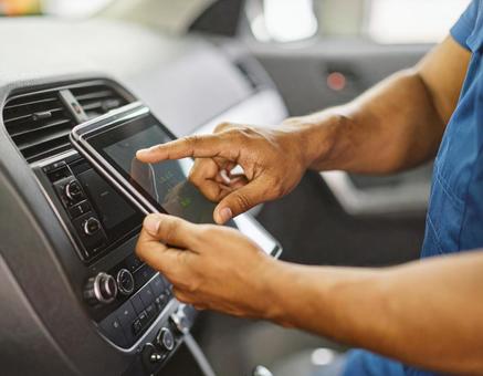 車内で診断タブレットを操作する整備士 車内で診断タブレットを操作する整備士の写真