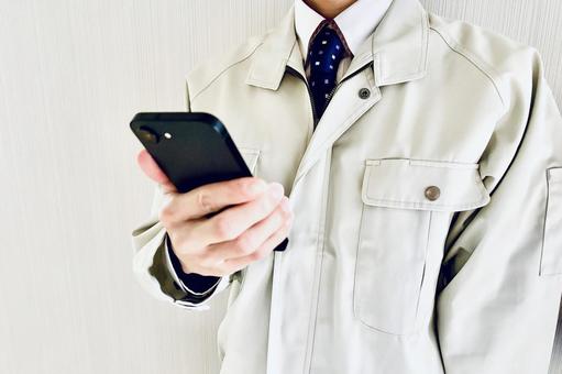スマホを持つ作業着姿の男性ビジネスマン スマホ,携帯,連絡の写真素材
