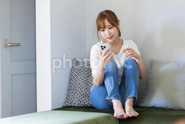 ソファでスマホを見てくつろぐ女性 リビング,女性,マグカップの写真素材
