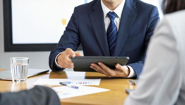 タブレットを使って説明する男性営業マンの写真