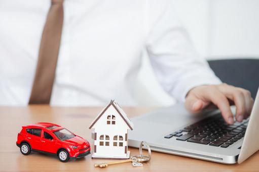 家と車の模型を前にして仕事をする手元 保険業,事務職,接客業の写真素材