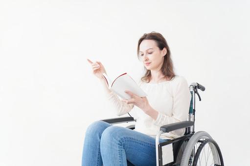 車椅子に乗り読書をする外国人の女性 車椅子に乗り読書をする外国人の女性 障害,電動車椅子,ヨーロッパ人の写真素材