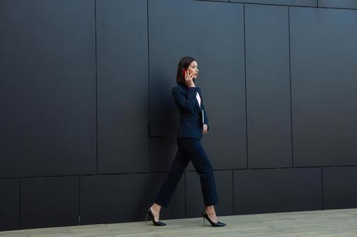 オフィスビルの外で歩きながら電話している横向きのビジネスウーマン ビジネスウーマン,ビジネス,女性の写真素材