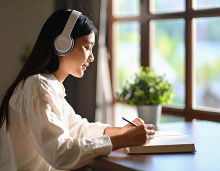 お気に入りの音楽を聴きながら勉強する女性 お気に入りの音楽を聴きながら勉強する女性の写真