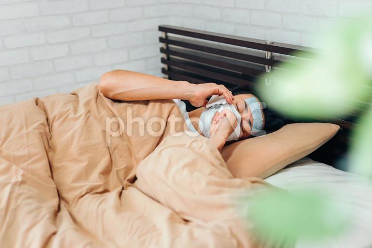 風邪をひいてベッドで寝る男性（スマホ） 発熱,通報,熱の写真素材