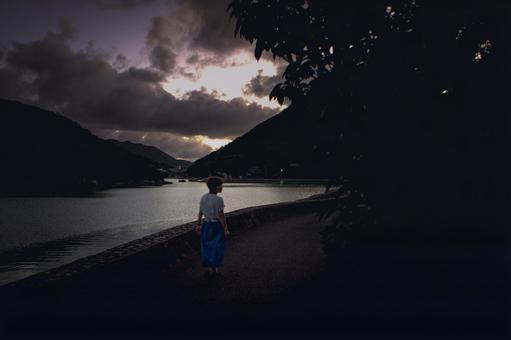 <素材>暗い夕暮れの海を一人散策する女性 <素材>暗い夕暮れの海を一人散策する女性の写真