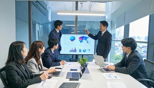 テーブルを囲んで会議するビジネスパーソンの写真