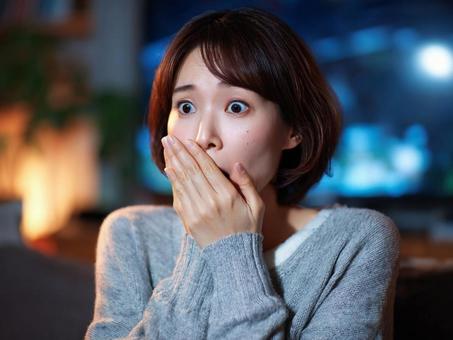 リビングで恐怖に驚く女性 リビングで恐怖に驚く女性の写真