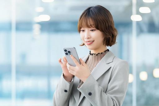 スマホを使う笑顔の女性・ビジネスウーマン 女性,スマホ,スマートフォンの写真素材