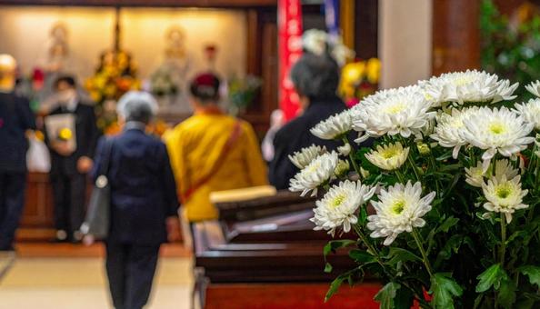葬儀場の白い花と葬式の弔問客の写真
