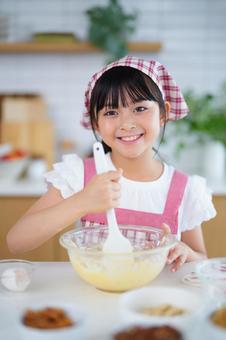 エプロンと三角巾姿でお菓子作りに挑戦する少女 女の子,小学生,日本人の写真素材