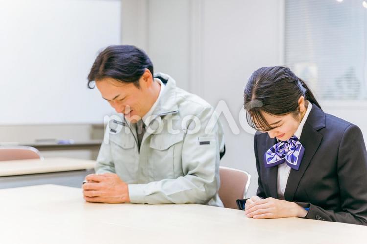 作業着を着た男性と事務スタッフの女性（お辞儀・笑顔） 作業服,工場,会議の写真素材