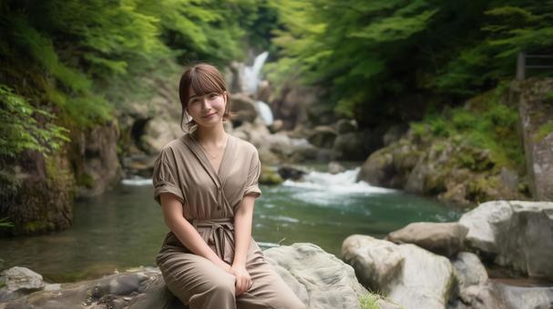 夏の深緑と渓流沿いの遊歩道と若い女性の写真