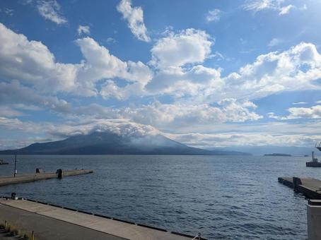 鴨池港から見た雲をかぶる桜島と青空 鴨池港から見た雲をかぶる桜島と青空 桜島,青空,雲の写真素材