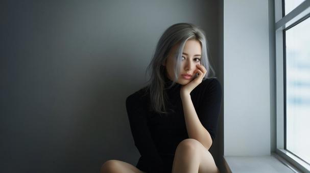 窓辺で頬杖をつく女性 窓辺で頬杖をつく女性の写真