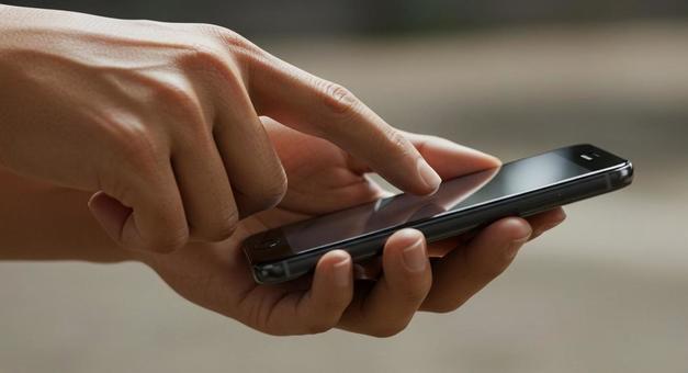 スマホを両手で操作する人 スマホを両手で操作する人の写真