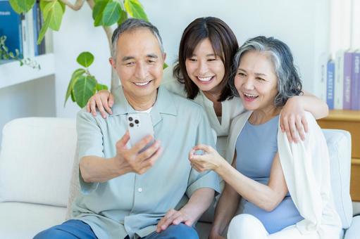 リビングでスマホを見るシニア夫婦と子供 シニア,夫婦,スマホの写真素材