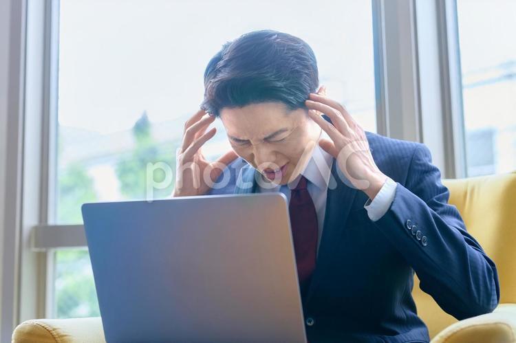 頭を抱えるビジネスマン　ノートパソコン ビジネスマン,トラブル,問題の写真素材