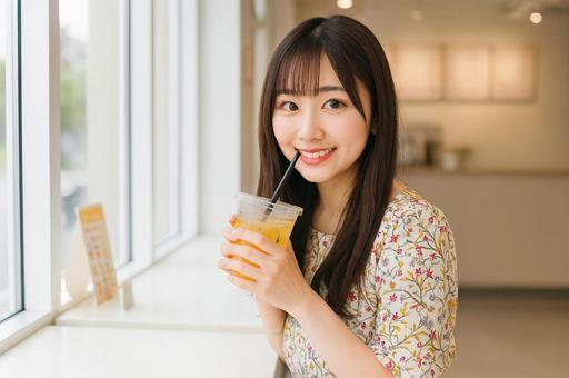 カフェでジュースを飲む笑顔の女性の写真