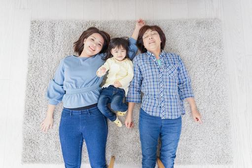 部屋で寝転ぶ子供と母とおばあちゃん 部屋で寝転ぶ子供と母とおばあちゃん 母親,幼児,絆の写真素材