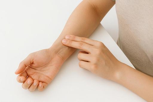 自分の脈をはかる女性の写真