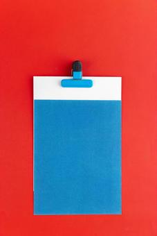 水色のクリップで挟まれた白と水色の紙(赤背景) 水色のクリップで挟まれた白と水色の紙(赤背景) モックアップ,物撮り,紙の写真素材