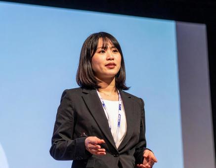 ステージ上でプレゼンをする女性 ステージ上でプレゼンをする女性の写真