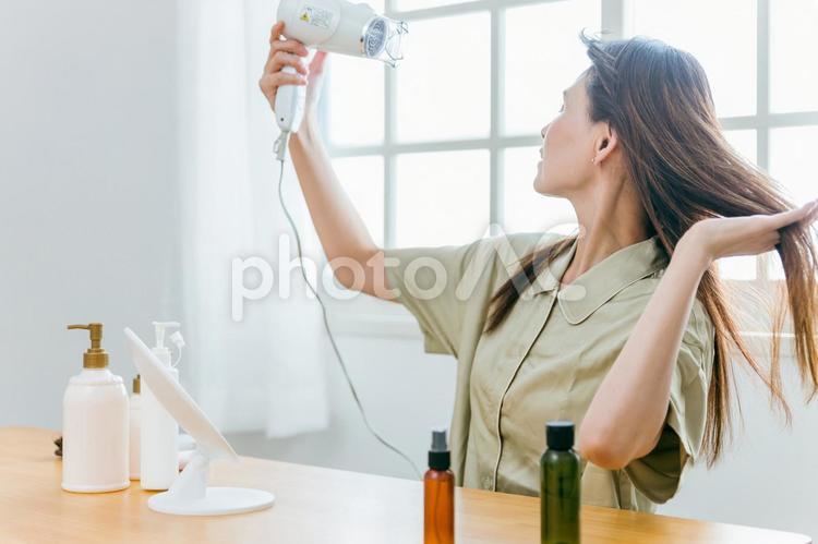 ドライヤーを使うミドル世代の女性（笑顔） ドライヤー,髪,女性の写真素材