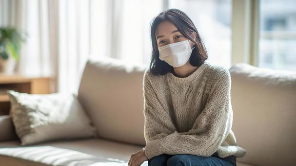 リビングでマスクをして休む女性02 リビングでマスクをして休む女性02の写真